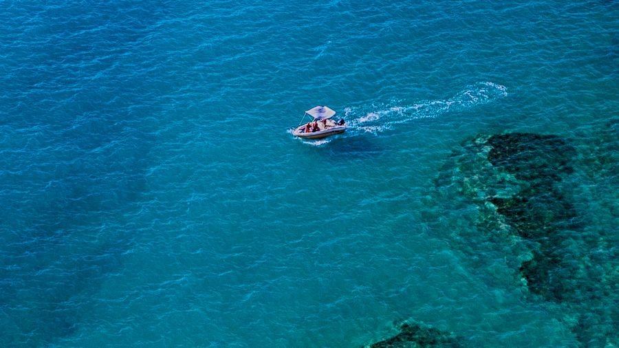 Barco com toldo navegando em águas cristalinas, vista aérea — seguro náutico e rastreador para lancha e jet ski
